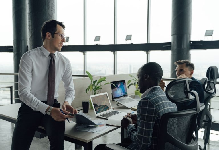 Three men engaged in a business meeting in a modern office setting with laptops and documents. — A New Player in Town: UFABET