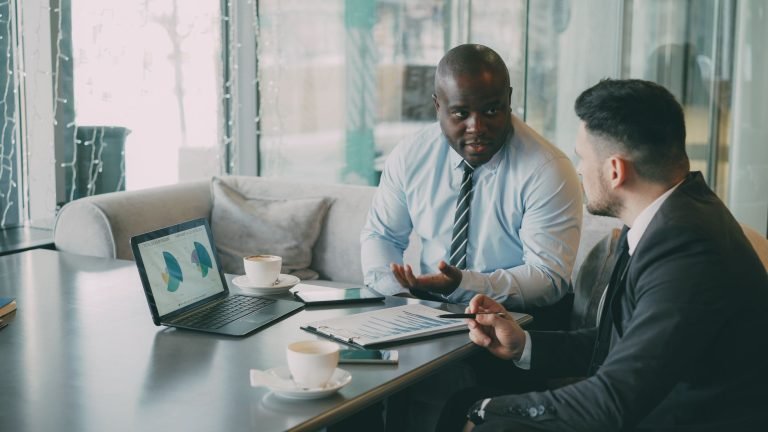 Two business professionals engaged in discussion over laptops and documents. — A Simple 30-Day Notice Prevents Misunderstandi
