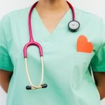 Close-up of a medical professional with a stethoscope and a paper heart cutout on a green uniform pocket. — Buy Trenbolone On