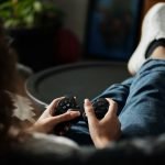 Close-up of woman gaming with a controller, feet propped up, enjoying leisure time indoors. — Enjoy Peace of Mind Knowing You