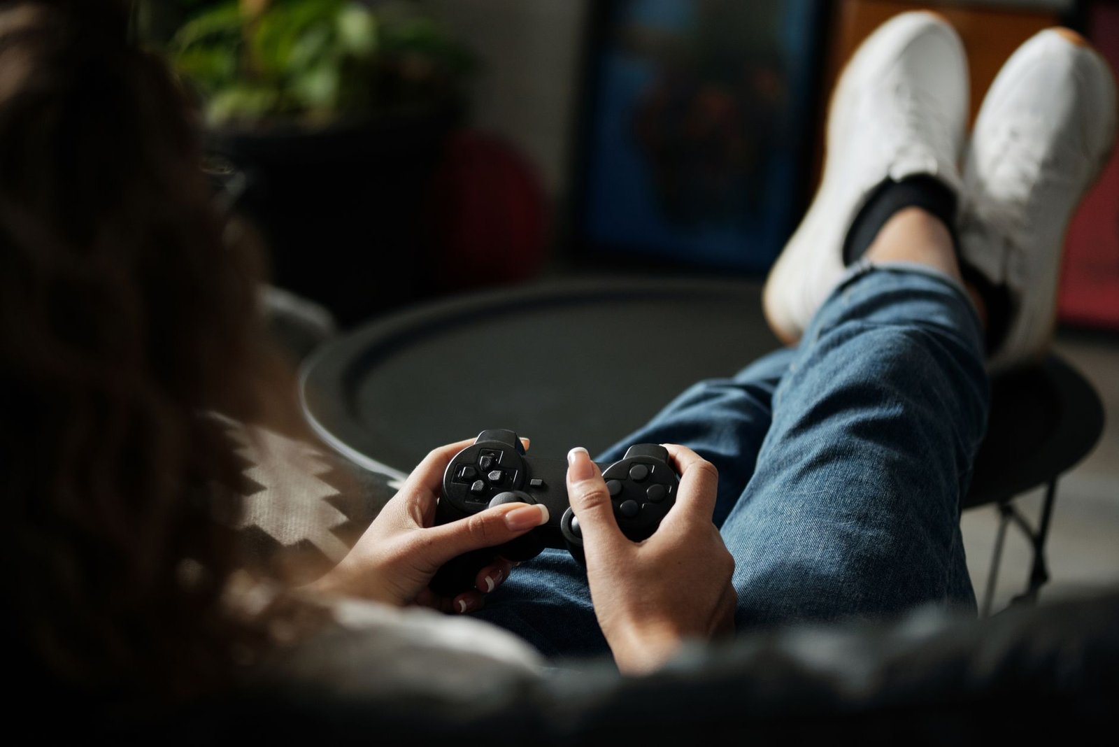 Close-up of woman gaming with a controller, feet propped up, enjoying leisure time indoors. — Enjoy Peace of Mind Knowing You