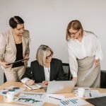Three businesswomen discussing documents during a meeting in a modern office setting. — Family-Friendly Restaurants in Madrid