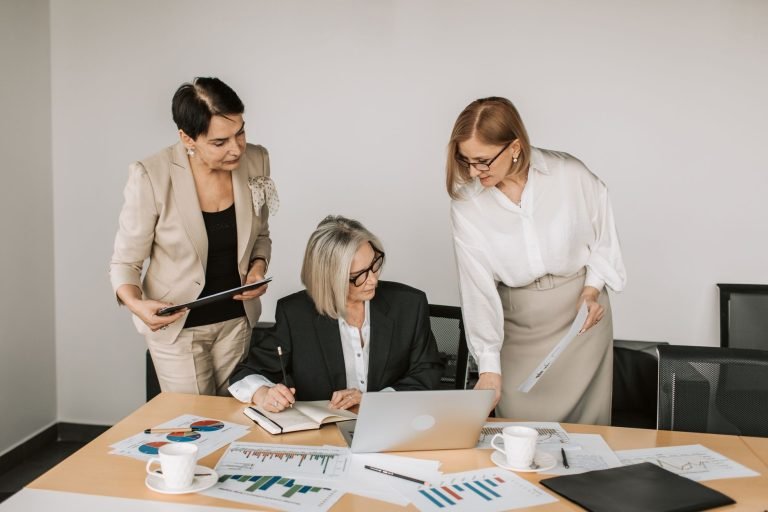 Three businesswomen discussing documents during a meeting in a modern office setting. — Family-Friendly Restaurants in Madrid