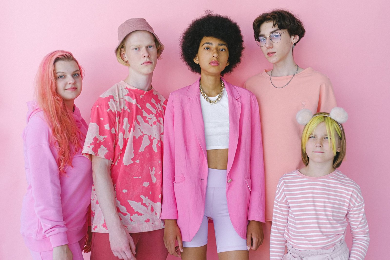 Group of multiracial teenage boys and girls looking at camera on pink background of studio — How Christian Necklaces for Wome