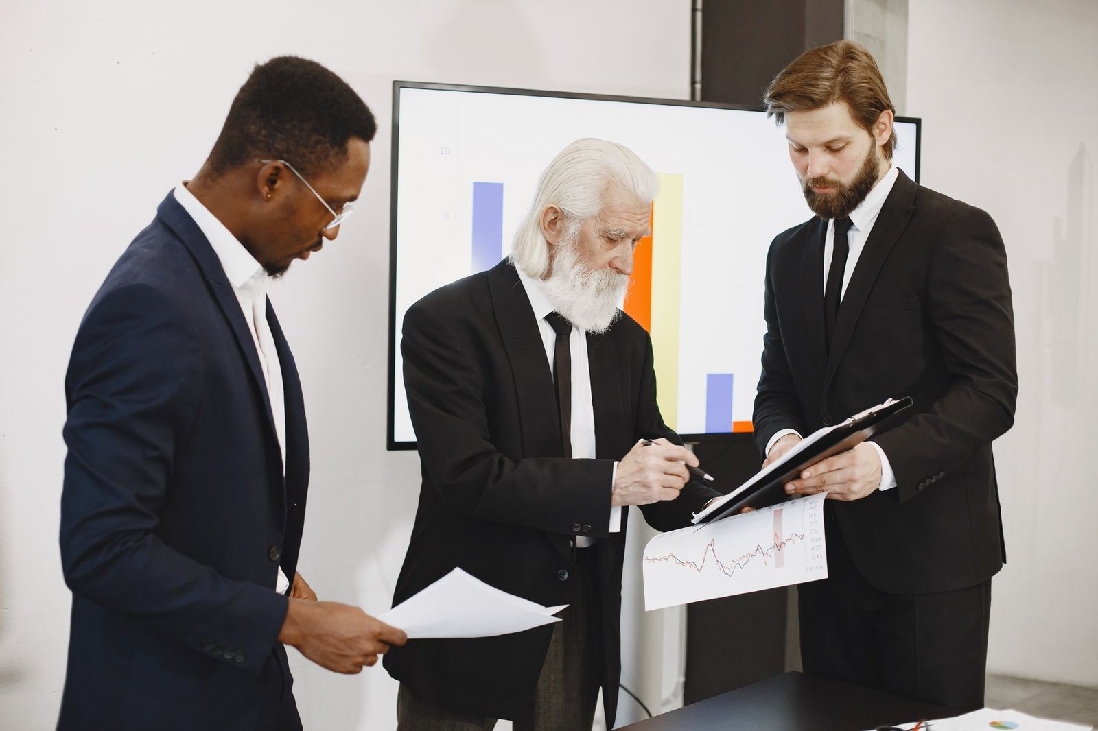 Three businessmen in suits reviewing reports and graphs during an office meeting. — Make the Most of your Bankroll: Strategie
