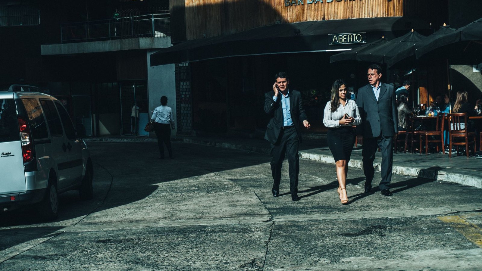 Three business professionals walk along a city street outside a cafe. — Navigating Employment Challenges in Entertainment Est
