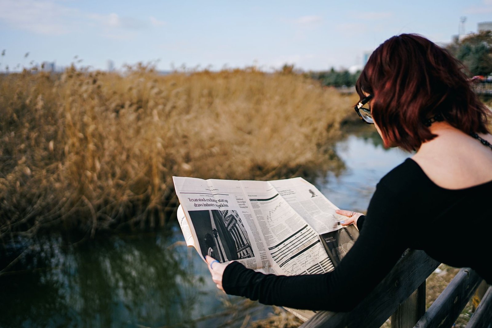 A woman reads a newspaper by a river, surrounded by autumn reeds and tranquil scenery. — New Social Security Rules That May A