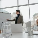 Professionals engaged in a collaborative business meeting with charts and laptops in a modern office setting. — The Benefits