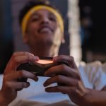 A relaxed gaming session with a close-up view of a man holding a game controller indoors. — The Difference Between Mini-Bacca