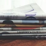 A stack of folded newspapers placed on a wooden table, symbolizing news and information. — The Tools and Techniques of Advanc