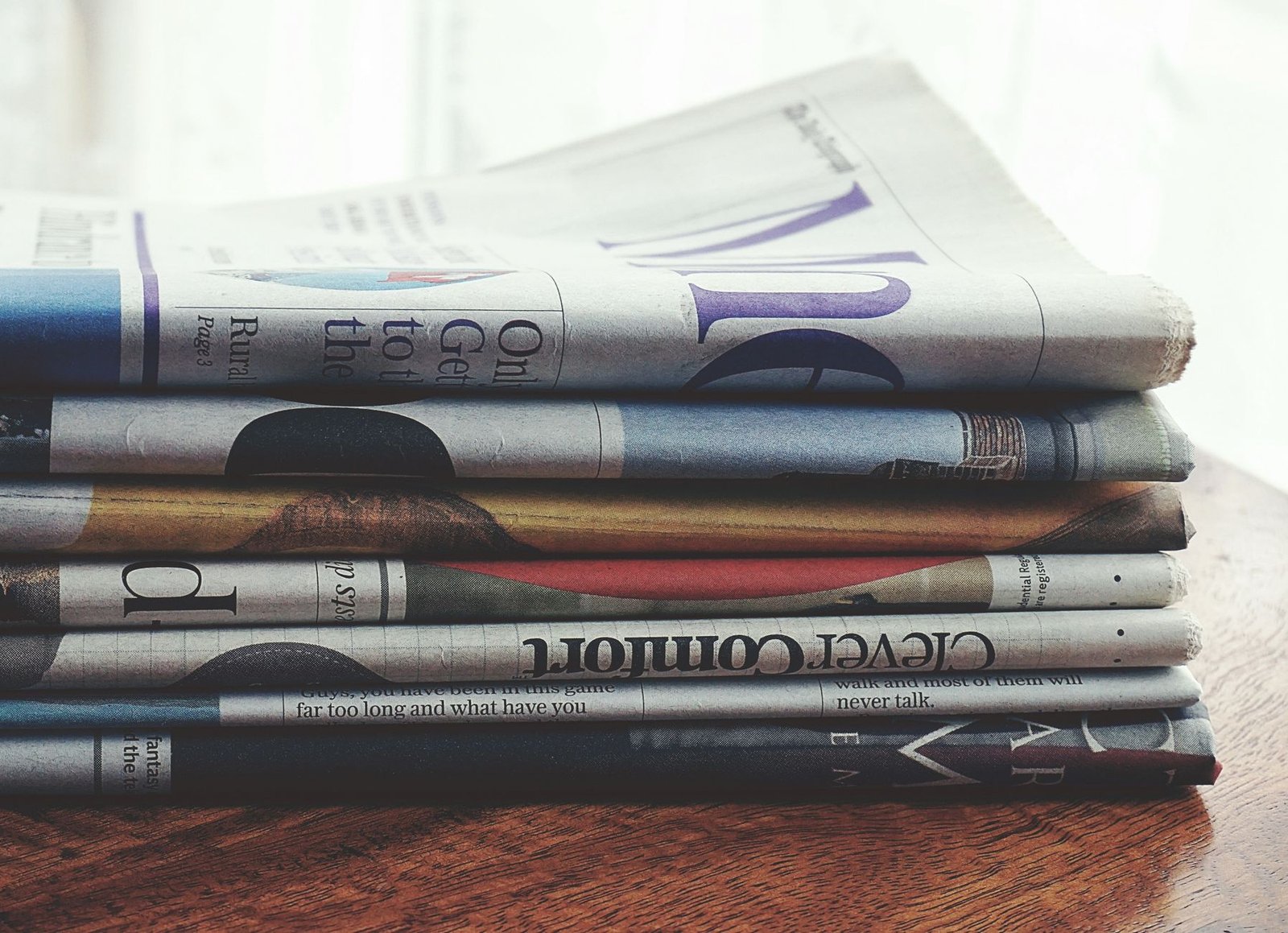 A stack of folded newspapers placed on a wooden table, symbolizing news and information. — The Tools and Techniques of Advanc