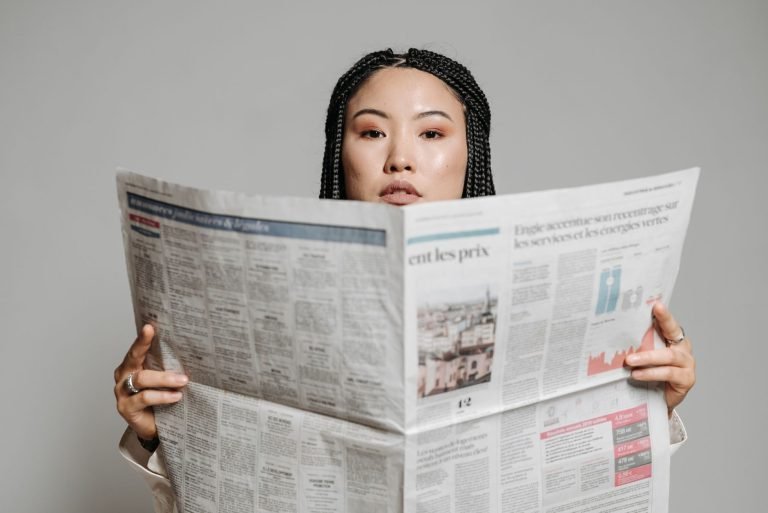 Asian woman with braided hair reading a newspaper in a studio setting. — Top Medicare Advantage Plans to Consider for 2026